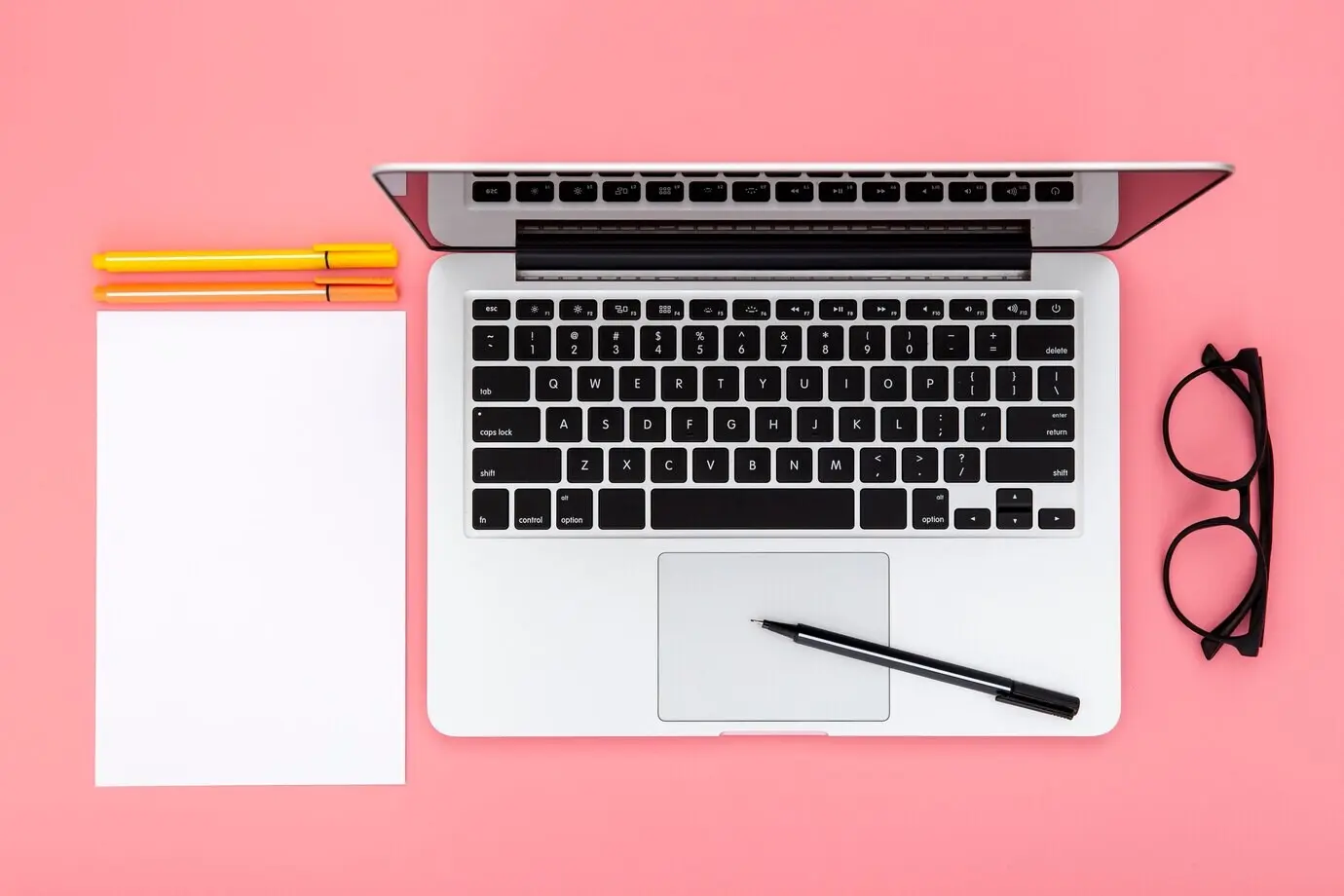 Anordnung von Schreibtischelementen auf pinkem Hintergrund